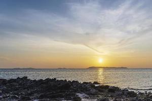 bel mare al crepuscolo. silhouette roccia sulla spiaggia contro il cielo durante il tramonto. sole che tramonta all'orizzonte per la libertà e l'inizio del concetto di vita. foto