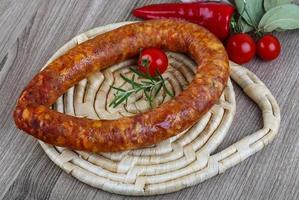 anello di salsiccia sul piatto di legno e sullo sfondo di legno foto