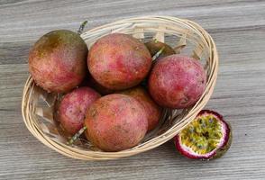 frutta tropicale fresca - maracuja in un cestino su fondo di legno foto