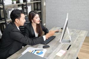 uomo d'affari che mostra qualcosa al collega sul computer desktop in ufficio. uomo d'affari e donna che lavorano insieme foto