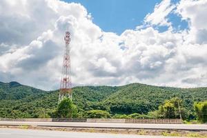 torre di telecomunicazione del telefono cellulare con nuvola bianca e sfondo di montagna con cielo blu foto