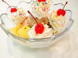 palline di gelato con panna montata e ciliegia foto