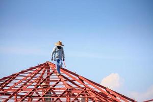 lavoratori del saldatore che installano la struttura del telaio in acciaio del tetto della casa in un cantiere edile foto