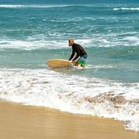 surfista al mare è in piedi con una tavola da surf foto