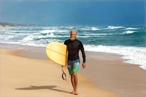 surfista al mare è in piedi con una tavola da surf foto