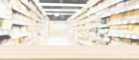 piano del tavolo in legno con sfondo sfocato corridoio del supermercato per la visualizzazione del prodotto foto