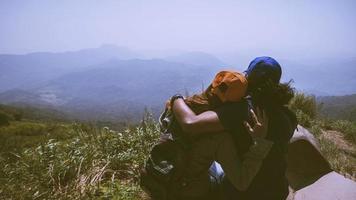 amante donne e uomini asiatici viaggiano rilassarsi durante le vacanze. sedersi e guardare il paesaggio sulla montagna. parco di montagna felicemente. in Thailandia foto