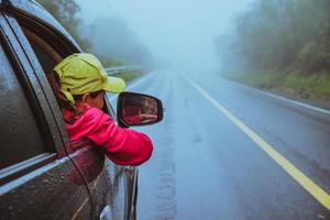 le donne asiatiche viaggiano rilassarsi durante le vacanze. guidare un'auto viaggiando felice. in mezzo alla nebbia piovosa. foto