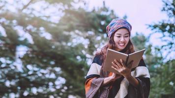 natura di viaggio donna asiatica. viaggiare rilassati. studio leggere un libro. educazione alla natura scrivere una nota al parco pubblico in estate. in Thailandia foto