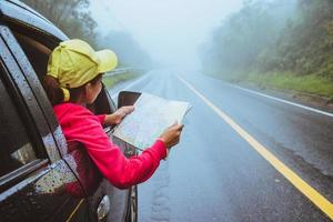 le donne asiatiche viaggiano rilassandosi durante le vacanze. viaggiare in parcheggio. visualizza la mappa per le escursioni nella natura durante la stagione delle piogge. foto