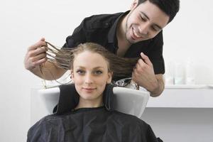 donna che sorride con il parrucchiere che esamina i suoi capelli al salone foto