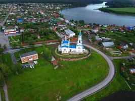 un vecchio villaggio di chiesa ortodossa sulla riva del fiume. vista a volo d'uccello foto