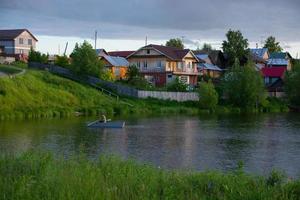 un villaggio sulla riva del fiume con erba verde brillante e un bel cielo. foto