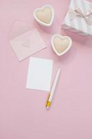 buona composizione di san valentino. mockup di biglietto di auguri vuoto, scatole regalo, cuori, coriandoli su sfondo rosa foto