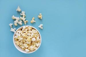 popcorn rovesciato su sfondo blu. concetto di notte di film. copia spazio per il testo foto