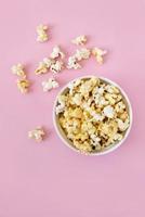 popcorn rovesciato su sfondo rosa. concetto di notte di film. copia spazio per il testo foto