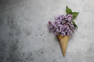 cono gelato con fiori colorati su sfondo grigio. disteso. concetto estivo minimo. foto