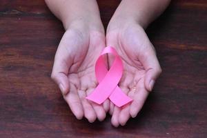 il nastro rosa in mano, simbolo della campagna mondiale contro il cancro al seno delle donne. foto