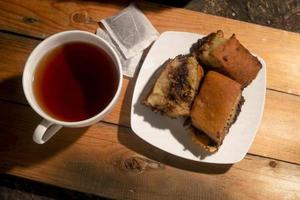 torta al cioccolato con una tazza di tè sulla tavola di legno. menù della colazione al mattino foto