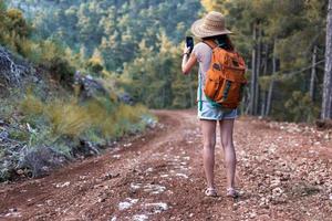 una ragazza fotografa un bellissimo paesaggio di montagna su uno smartphone foto