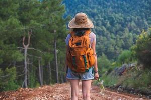 una donna con uno zaino e un cappello di paglia su un sentiero di montagna foto