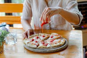 luce soffusa e immagine sfocata, pizza fatta in casa con crosta sottile di pizza con frutti di mare e formaggio per l'intera gamma servita su un vassoio rotondo di legno ai clienti. copia spazio per inserire il testo. foto