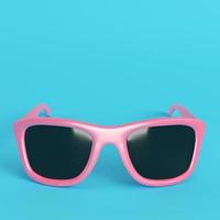 occhiali da sole rosa con lenti nere su sfondo azzurro brillante in colori pastello foto