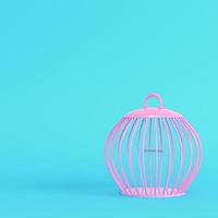 gabbia per uccelli rosa su sfondo blu brillante in colori pastello foto