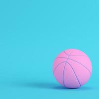 palla da basket rosa su sfondo blu brillante in colori pastello. concetto di minimalismo foto