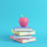 mela rosa su una pila di libri su sfondo blu brillante in colori pastello foto