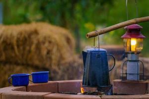 bollitore vintage smaltato sulla stufa a legna al mattino campeggio bollitore per caffè antico. falò in campagna.messa a fuoco morbida. foto