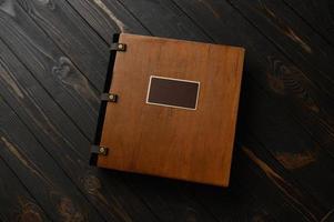 un vecchio album fotografico con copertina in legno e scudo su un tavolo rustico. logo gratuito foto