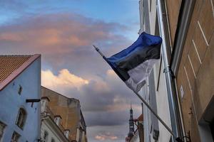 vista ad angolo basso della bandiera estone che sventola contro gli edifici in città durante il tramonto foto
