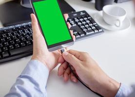 uomo che tiene il telefono con schermo verde con batteria in carica foto