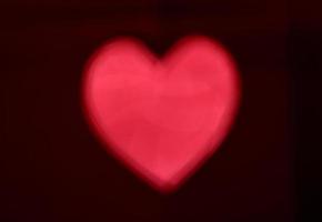 sfocatura rossa a forma di cuore di ligth bokeh su sfondo nero foto