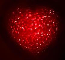 sfocatura rossa a forma di cuore di ligth bokeh su sfondo nero foto