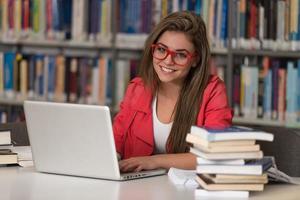 giovane studente che utilizza il suo computer portatile in una biblioteca foto
