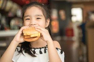 i bambini asiatici mangiano il food court dell'hamburger del formaggio di pollo foto