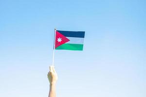 mano che tiene la bandiera della giordania sullo sfondo della natura. giorno dell'indipendenza della giordania e concetti di celebrazione felice foto
