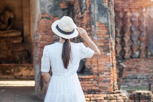 donna turistica in abito bianco in visita all'antico stupa nel tempio di wat chaiwatthanaram nel parco storico di ayutthaya, estate, asia e thailandia concetto di viaggio foto