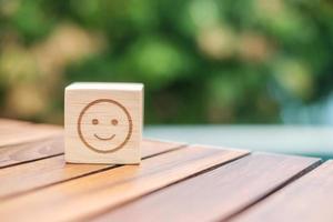 sorriso emozione faccia simbolo su blocchi di legno. valutazione del servizio, classifica, recensione del cliente, soddisfazione, valutazione e concetto di feedback foto