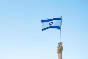 mano che tiene la bandiera israeliana sullo sfondo della natura. giorno dell'indipendenza di israele e concetti di celebrazione felice foto