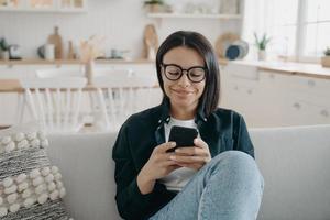 la donna felice sta chattando al telefono a casa. la ragazza sta scrivendo e sorridendo, ricevendo messaggi. foto