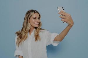 bionda adolescente prendendo selfie mentre sorride foto