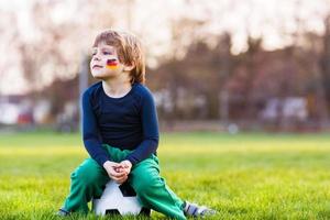 un ragazzo biondo di 4 che gioca a calcio con il campo di calcio onl