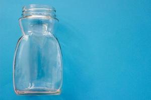 bottiglia vuota di vetro trasparente su sfondo blu con posto per il tuo design. foto