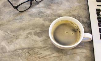 tazza di caffè bianca in ceramica su un tavolo di cemento rustico. foto