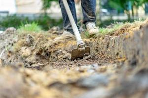 il giardiniere scava il terreno con la sua attrezzatura per il giardinaggio e prepara il terreno per la piantagione. foto