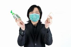 l'uomo asiatico tiene e mostra la pulizia del gel di alcol e del sapone sulla mano e indossa una maschera nera su sfondo bianco chiaro. foto