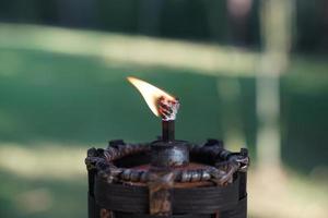 primo piano torcia e fuoco in giardino con sfocatura dello sfondo verde. foto